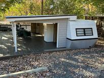 A charming exterior view with a covered deck and a well-maintained white and gray camper at 112 Sycamore St, New London, NC 28127