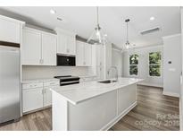 Bright modern kitchen featuring white cabinetry, stainless steel appliances, and a quartz countertop island at 1428 Hamilton St # 13, Charlotte, NC 28206