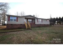 Ranch style mobile home with brick skirting, deck, and spacious yard at 4223 Old Catawba Rd, Claremont, NC 28610