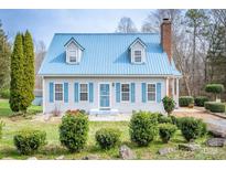 Charming home featuring a light blue metal roof, lush landscaping, and welcoming front yard at 166 Rosalind Ln, Statesville, NC 28677