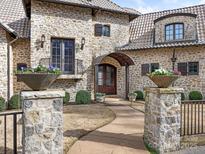 Stunning stone home featuring a beautiful arched doorway, stone pillars with flower planters, and a curved walkway at 8525 Double Eagle Gate Way # 2, Charlotte, NC 28210