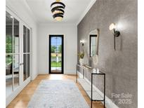 Elegant foyer with stylish lighting, decorative mirror, console table, and view of the outdoors through a black framed door at 4142 Pineview Rd, Charlotte, NC 28211