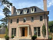 Stunning brick two-story home featuring a welcoming portico entry and symmetrical window design, complete with manicured landscaping at 1969 Maryland Ave, Charlotte, NC 28209