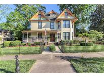 Charming two-story home featuring a covered front porch, colorful accents, and mature trees in a desirable neighborhood at 235 Walnut St, Statesville, NC 28677