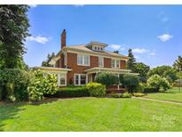 Charming two-story brick home featuring a well-manicured lawn and beautiful landscaping at 215 N Main St, Belmont, NC 28012