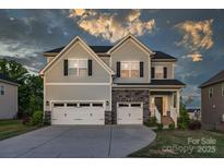 Two-story house with gray siding, stone accents, and a three-car garage at 4212 Linville Way, Fort Mill, SC 29707