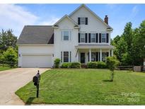 Charming two-story home features a well-manicured lawn, a classic white exterior, and inviting front porch at 5535 Whispering Wind Ln, Indian Trail, NC 28079