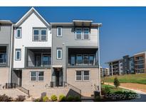 Modern townhome with gray siding, brick accents, black trim, balcony, and well-manicured landscaping at 320 Ferebee Pl # Brx0021, Charlotte, NC 28213