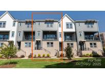 View of the townhome exterior with gray siding, brick accents, and a small front yard at 312 Ferebee Pl # Brx0023, Charlotte, NC 28213