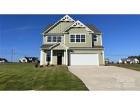 Inviting two-story home featuring a spacious driveway, a two-car garage, and a beautifully landscaped lawn at 11507 Valley Oaks Ln, Stanfield, NC 28163