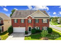 Charming two-story brick home featuring green shutters and a well-manicured front lawn at 14447 Waterlyn Dr, Charlotte, NC 28278