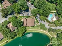 Aerial view of complex featuring a pond, swimming pool, and mature landscaping on a sunny day at 7378 Winery Ln, Charlotte, NC 28227