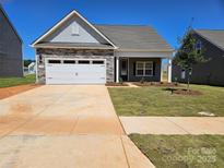 Charming single-story home featuring a stone facade, a two-car garage, and a well-manicured lawn at 126 Brixham Loop, Troutman, NC 28166