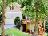 Two-story house with large deck and attached garage, nestled in a wooded area at 9004 Cebu Ct, Tega Cay, SC 29708