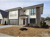 Modern two-story home with stone accents and a gray metal garage door at 13217 Terrace Court Dr, Charlotte, NC 28278