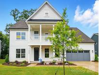 Charming two-story home with gray garage, covered porch and manicured landscaping at 2027 Cedar Falls Dr # 75, Waxhaw, NC 28173