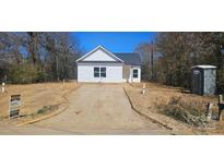 Charming single-story home with white siding, a black roof, and visible construction progress in the front yard at 1011 Indiana St, Kannapolis, NC 28083
