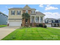 Inviting two-story home with a covered porch, manicured lawn, stone accents, and attached two-car garage at 135 Tenth Green Ct, Statesville, NC 28677