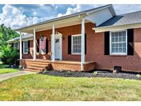 Brick home with a large front porch and American flag at 2909 Eastway Dr, Statesville, NC 28625