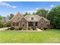 Charming brick and stone home featuring manicured lawn, tasteful landscaping, and inviting front porch at 160 Northington Woods Dr, Mooresville, NC 28117