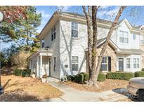 Charming townhouse with white siding and brick accents under a blue sky with mature tree and walkway at 12229 Savannah Garden Dr, Charlotte, NC 28273