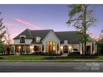 Elegant home with lush landscaping, large windows, a porte cochere, and a serene twilight sky at 18304 Rosapenny Rd, Charlotte, NC 28278