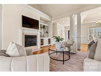 Bright living room featuring a fireplace, built-in shelving, hardwood floors, and neutral-toned furniture at 2504 Stoneview Ct, Denver, NC 28037