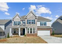 Beautiful two-story home showcasing stone facade, blue shutters, and a well-manicured lawn under a bright sky at 121 Clawton Loop, Mooresville, NC 28115