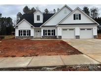 Two-story house with white siding, gray stone accents, and a three-car garage at 130 Falls Leaf Dr # Lot 4, Troutman, NC 28166