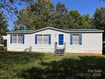 Charming single-story home with blue shutters and door nestled among lush trees at 6261 Burnhurst Ln, Denver, NC 28037
