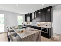 Modern kitchen features a center island with seating, sleek black cabinetry, and elegant marble backsplash at 5225 Glenwalk Dr # 0061, Charlotte, NC 28269