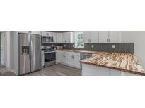 Modern kitchen featuring stainless steel appliances, white cabinets, and butcher block countertops at 55 Shannon Park Cir, Taylorsville, NC 28681