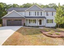 Charming two-story home with light blue siding, black shutters, and a brick-accented two-car garage at 1133 Heather Oak Ln, Oakboro, NC 28129
