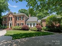 Stately brick home featuring a well-manicured lawn, mature landscaping, and a circular driveway at 4301 Fairview Oaks Dr, Charlotte, NC 28211
