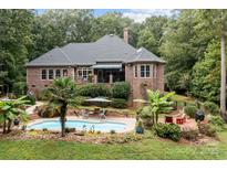 Stunning backyard features a brick home, pool, and beautiful landscaping for ultimate outdoor relaxation at 4364 Hager Mountain Ln, Iron Station, NC 28080