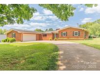 Charming brick ranch-style home with an attached two-car garage and a well-maintained lawn at 1405 Northcrest Dr, Albemarle, NC 28001