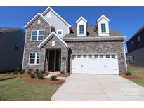 Two-story house with stone exterior, white garage door, and landscaping at 10108 Whitaker Pointe Dr, Huntersville, NC 28078