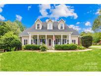 Charming home with a well-manicured lawn, rocking chair front porch, and a neutral color palette at 112 Berea Baptist Church Rd, Stanfield, NC 28163