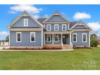 Charming two-story home featuring a covered front porch, brick accents, and a well-manicured lawn at 332 Canvasback Rd, Mooresville, NC 28117