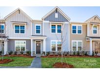 Modern three-story townhome with gray and beige siding, landscaping, and a walkway at 10513 Boudreaux St, Huntersville, NC 28078