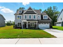 Charming two-story home with a well-manicured lawn, attached garage, and inviting covered entryway at 3229 Mcharney Dr # 30, Harrisburg, NC 28075