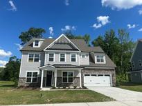 New two-story home featuring stone accents, a two-car garage, and a well-manicured lawn at 3229 Mcharney Dr # 30, Harrisburg, NC 28075