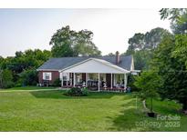 Charming brick home featuring a welcoming front porch and beautifully maintained lawn and landscaping at 3021 Davis Park Rd, Gastonia, NC 28052