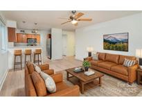 Living room with light brown sofas, coffee table, and kitchen area at 2423 Vail Ave # A12, Charlotte, NC 28207