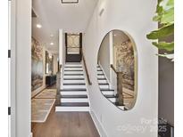 Bright entryway showcasing modern wood flooring, staircase, stylish decor, and an elegant oval mirror at 3016 Endhaven Terraces Ln # 11, Charlotte, NC 28277
