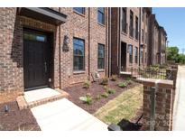 A brick townhome with a covered entry and landscaped front yard showcasing attractive curb appeal at 222 Gilead Rd, Huntersville, NC 28078