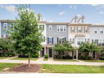 Three-story townhouses with gray and beige siding, landscaping, and a sidewalk at 9714 Ainslie Downs St, Charlotte, NC 28273