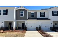 Charming townhome featuring a one-car garage, a modern exterior with a mix of white and gray siding, and a well-maintained lawn at 1636 Village Grove Ln, Monroe, NC 28110