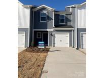 Charming two-story townhome with gray siding, a one car garage and well-maintained landscaping at 1636 Village Grove Ln, Monroe, NC 28110