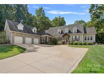 House exterior featuring stone accents, a three-car garage, and a manicured lawn at 162 Hoover Rd, Troutman, NC 28166